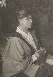 Alice Meynell seated, looking to the right, with knitting needles in her hand